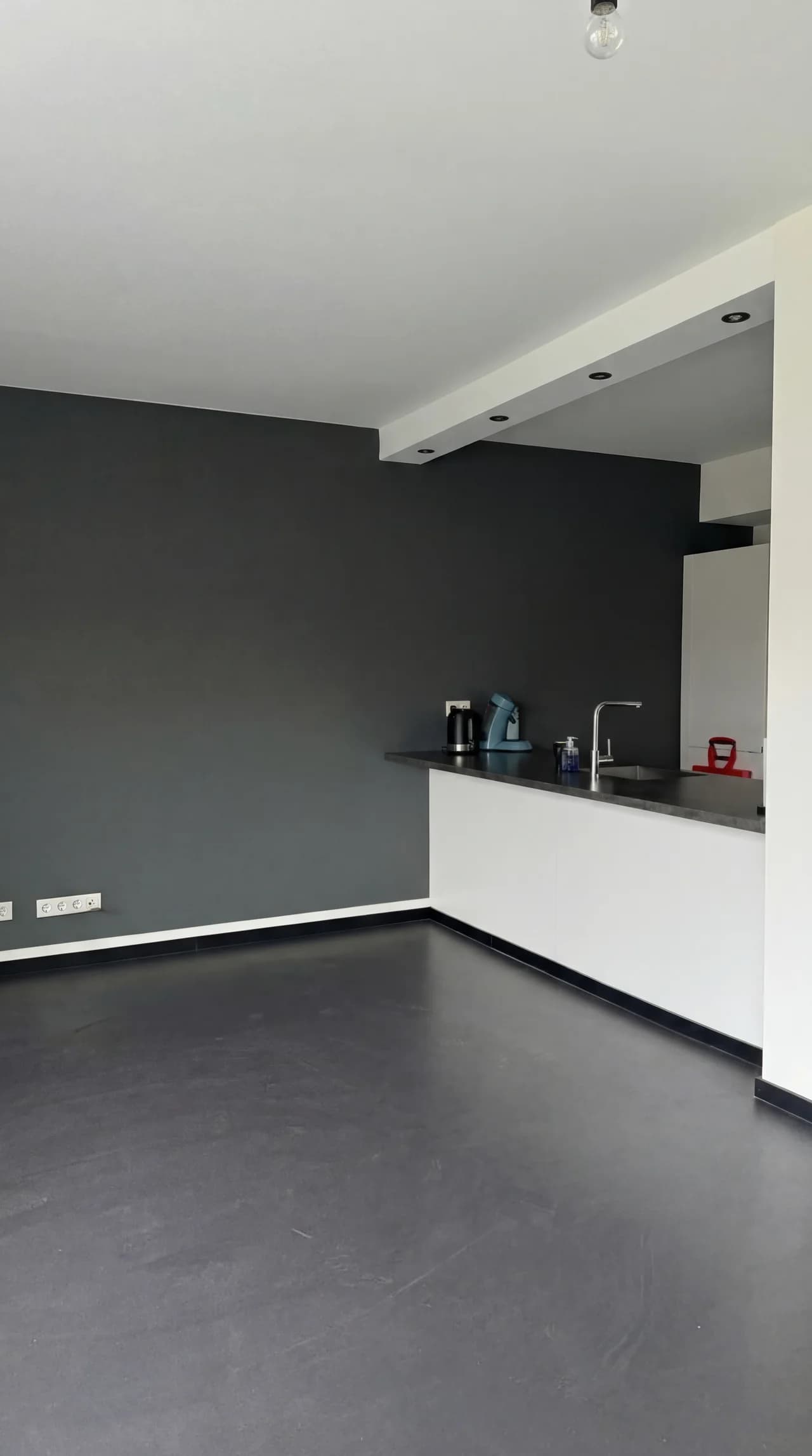 Donkergrijs gespoten latexwand in een open woonkeuken