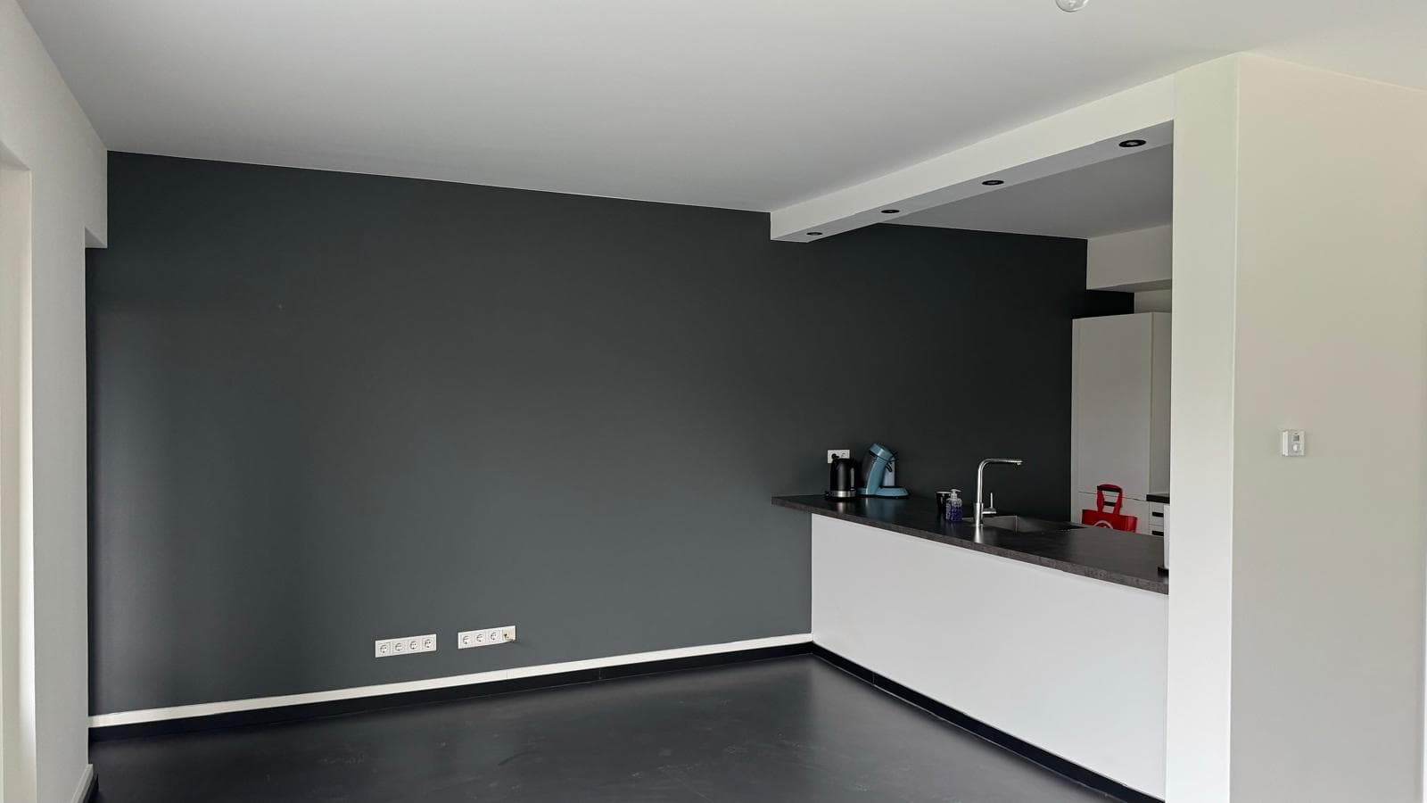 Door ons egaal gespoten antracietkleurige wand in een nieuwbouwwoning
