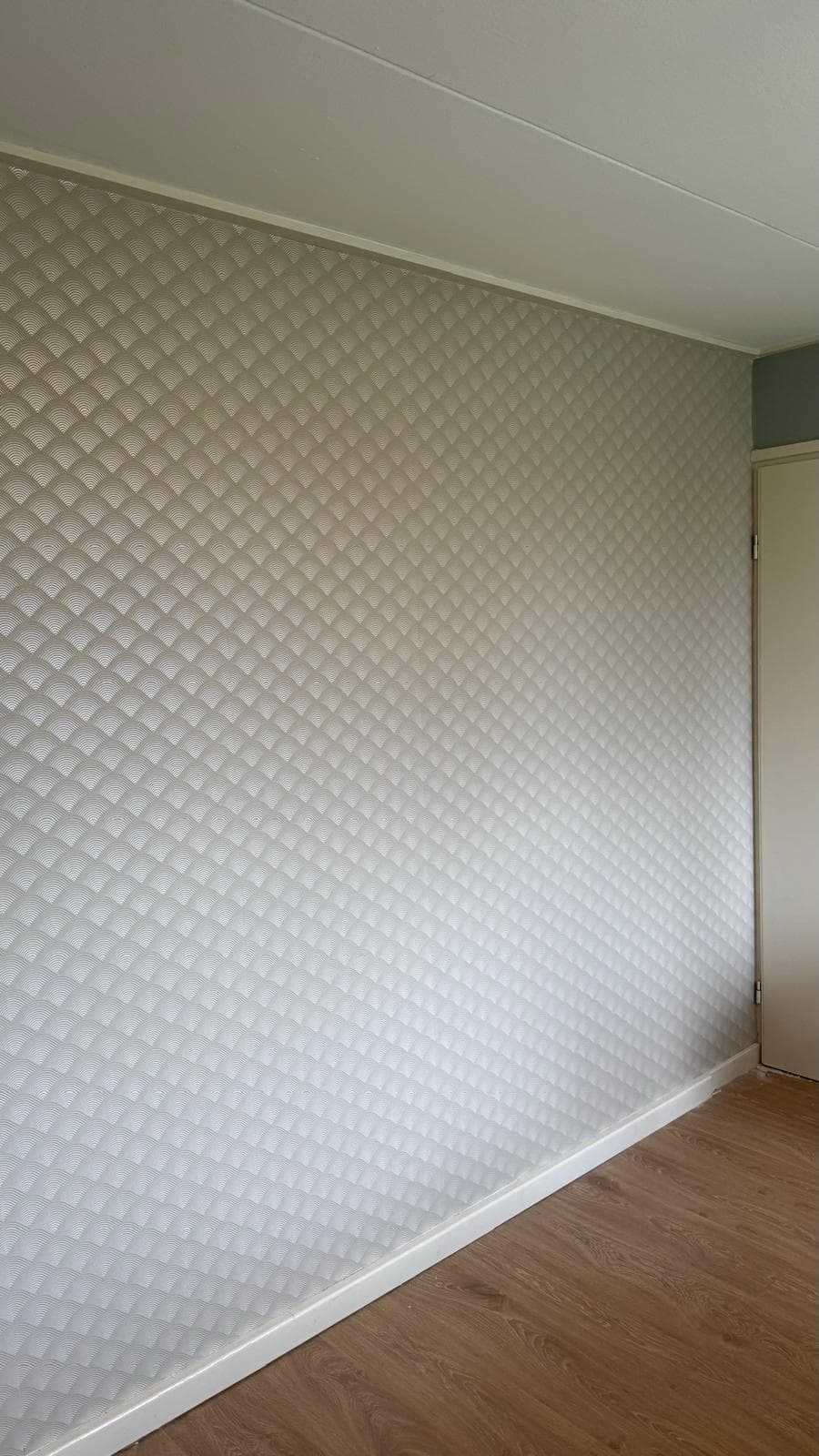 Wand met fijn structuurbehang, netjes afgewerkt tot op de plint